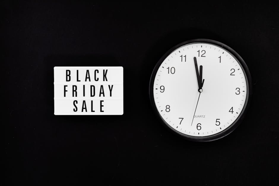 A close-up image featuring a white rectangular lightbox sign with black uppercase letters spelling 'BLACK FRIDAY SALE' positioned to the left, and a round white wall clock with black hour and minute h
